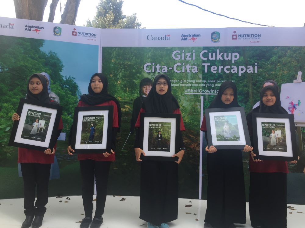 - Nutrition International Girls at the SGII launch in Indonesia hold frames with campaign photos
