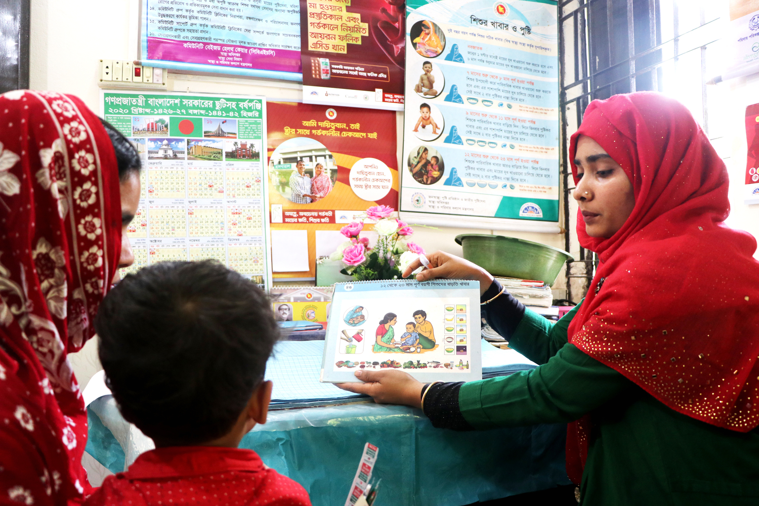 tania-health-worker-bci-zach-teck-bangladesh - Nutrition International health worker in Bangladesh uses educational materials to explain the importance of health and hygiene to a mother and child