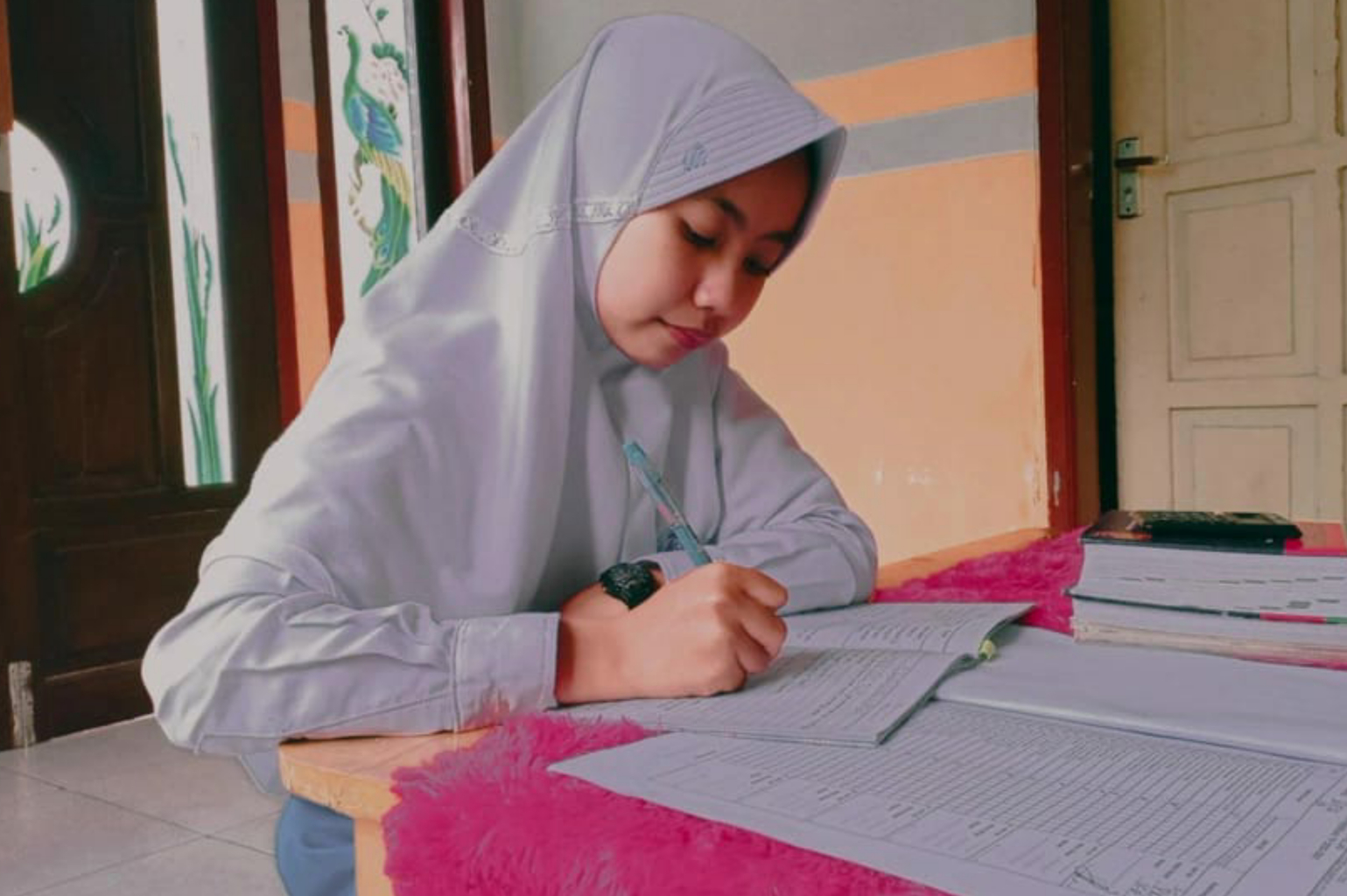 Sifaul Jannah_Indonesia_InShot_20210921_164146247 - Nutrition International Student in Indonesia sits at a table and does her homework.