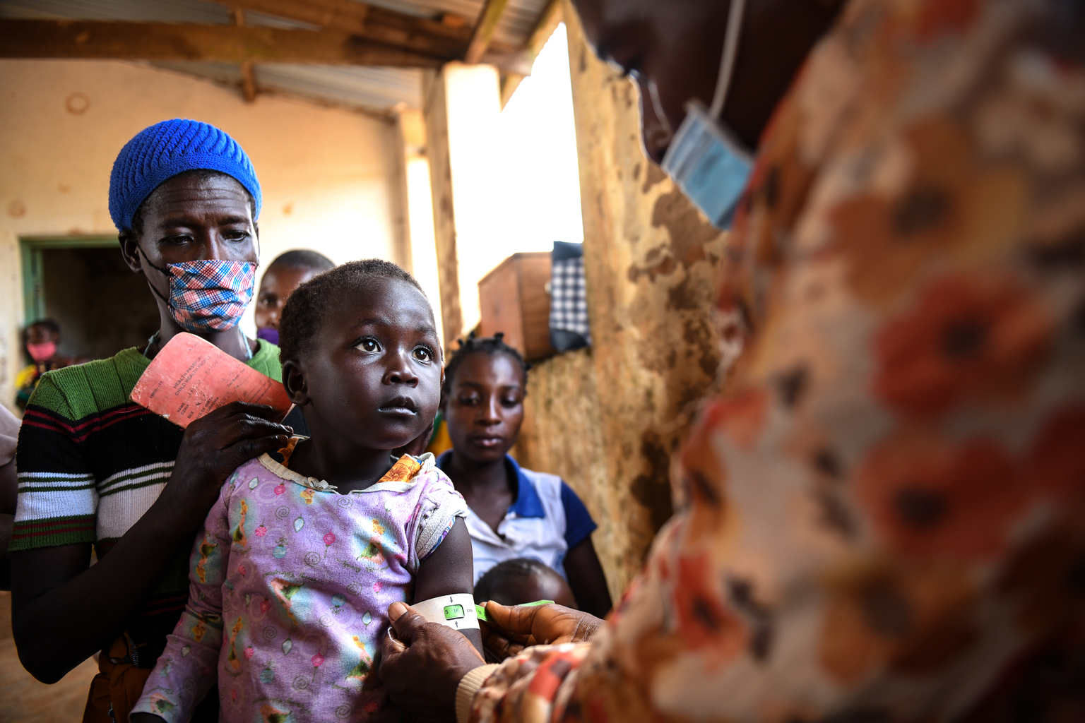 DSC_6492 - Nutrition International A health worker measures a young child girl growth who is sitting on her mother's lap at a health clinic in Malawi