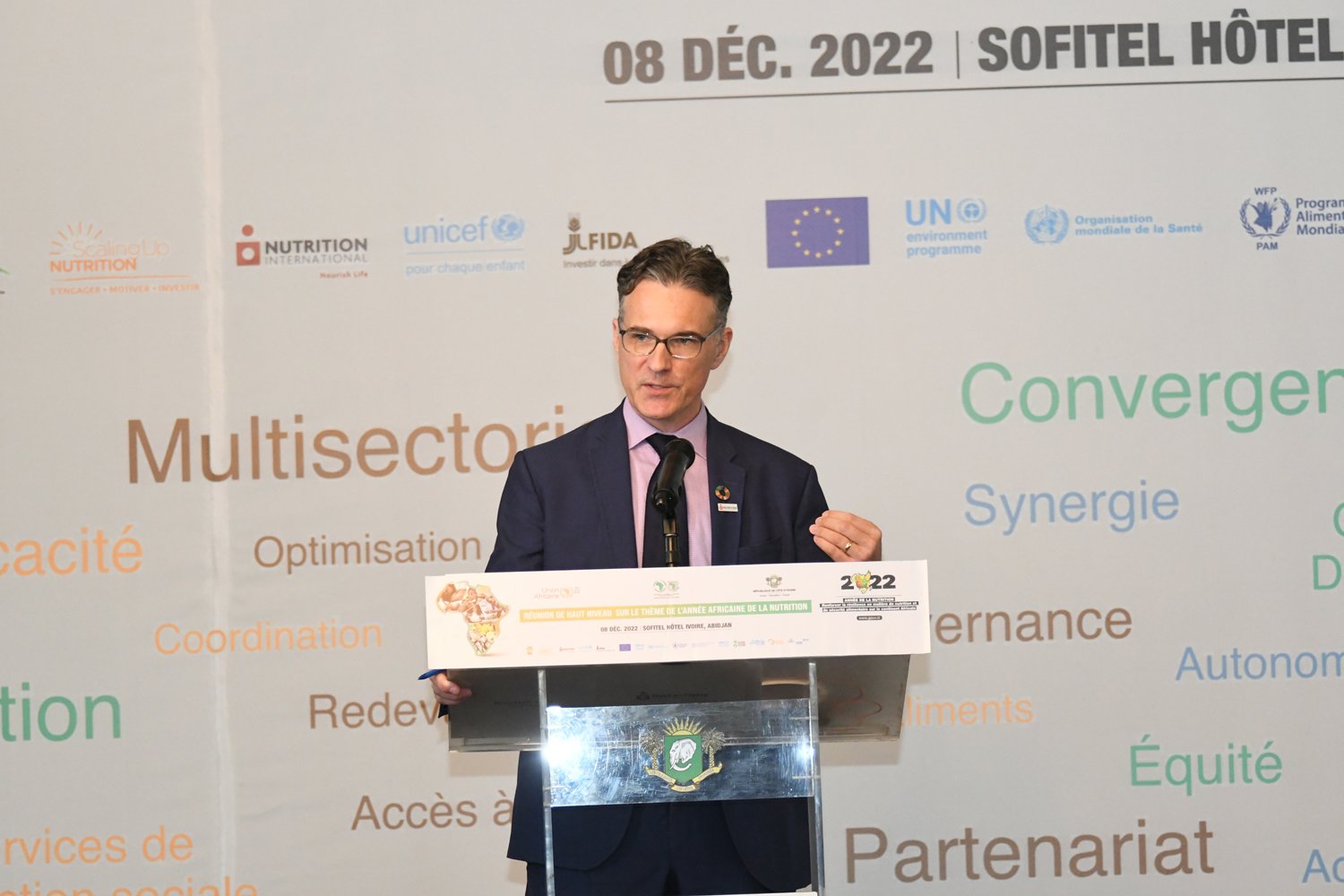 A man facing the camera gives a speech