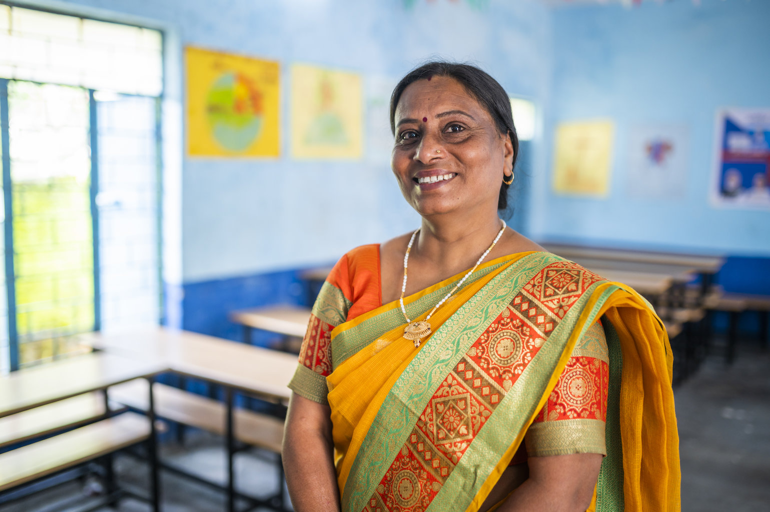 NI MP 2022 - Nutrition International A woman in an orange sari stands smiling