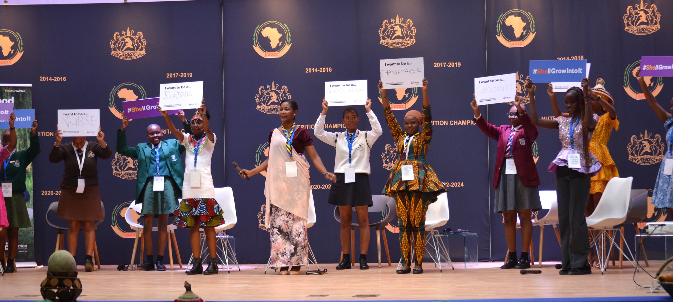 Group of adolescent girls facing the camera holding signs above head