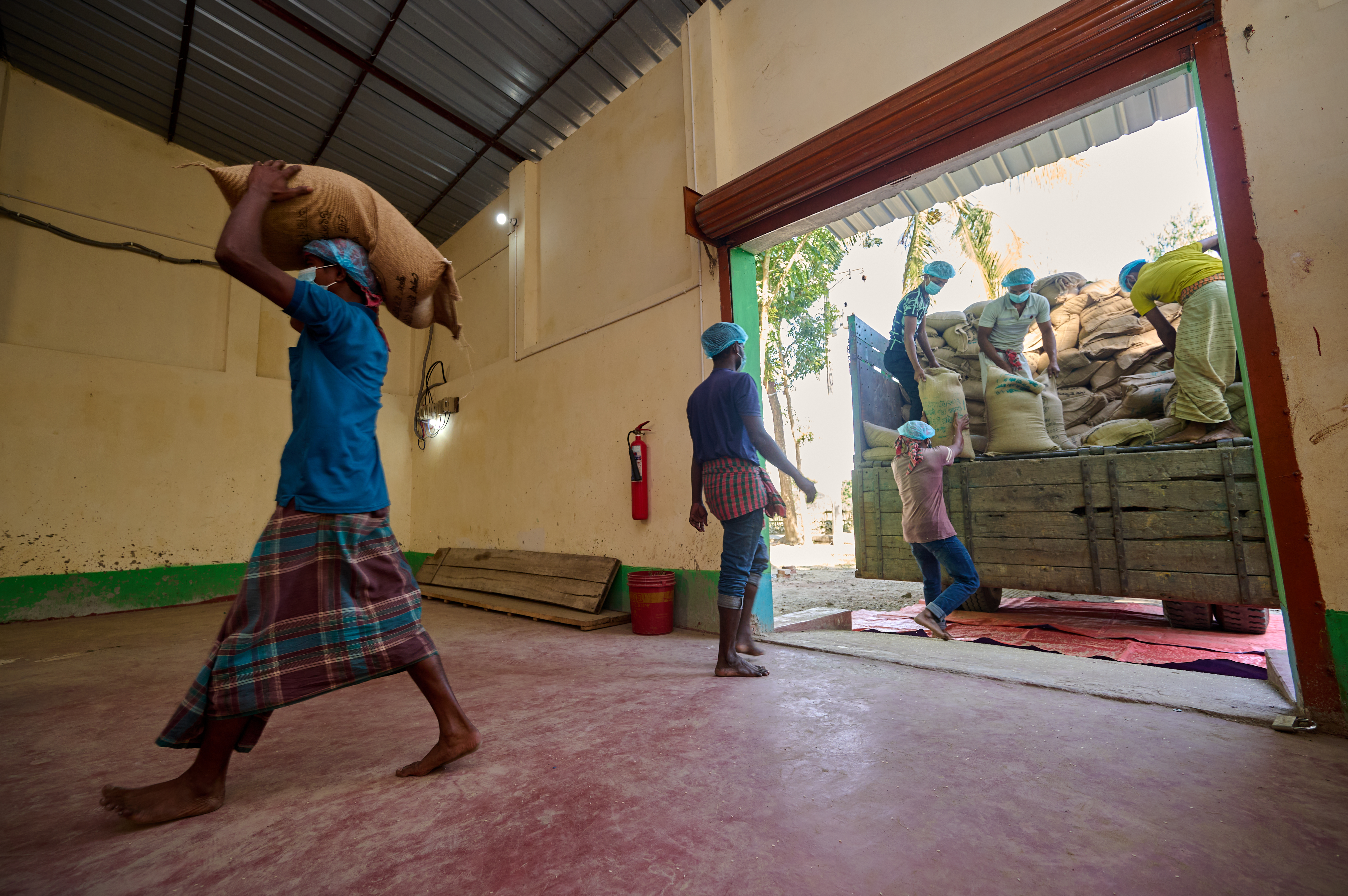 0080-NI-BD-20-11-2022-sujanmap - Nutrition International Workers carry sacks of non-fortified rice into a rice fortification blending facility in Jamalpur, Bangladesh.