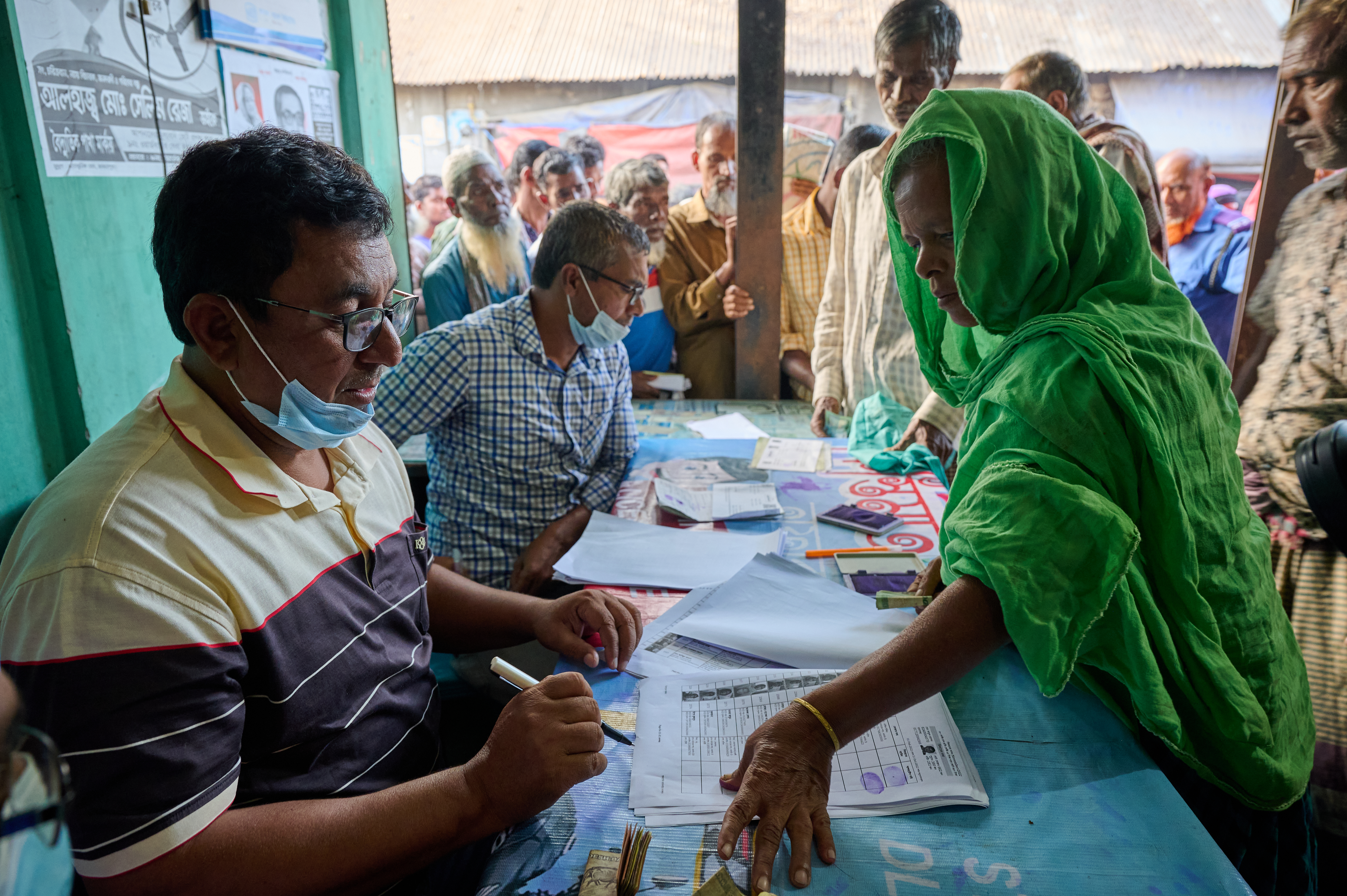 0173-NI-BD-21-11-2022-sujanmap - Nutrition International A woman registers at a distribution point to purchase fortified rice at a subsidized price through the Food Friendly Program in Bangladesh.