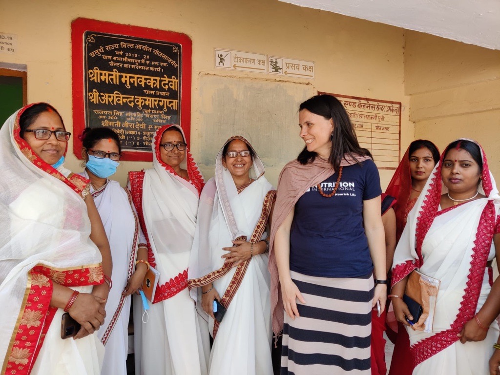 A group of women stand in a line facing the camera and laughing..