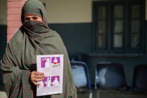 Sonia Hamid _ Pakistan - Nutrition International Sonia Hamid standing in front of camera holding up MMS brochure.